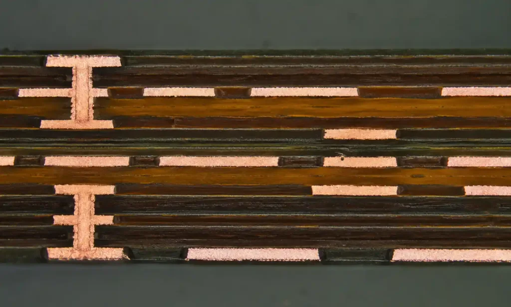 Microscopic cross-section of multilayer flexible PCB showing copper layers and dielectric materials