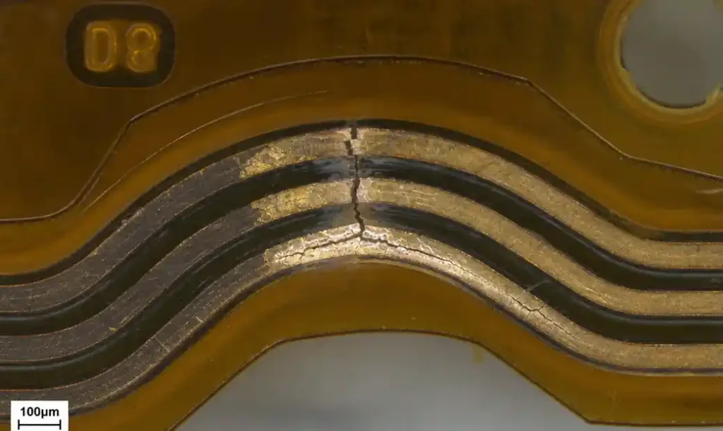 Microscope image showing copper trace crack failure at flex PCB bend location